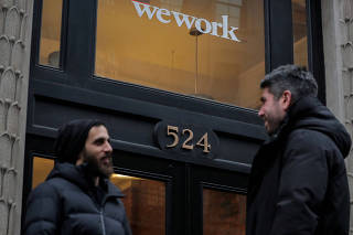 FILE PHOTO: People stand outside a WeWork co-working space in New York