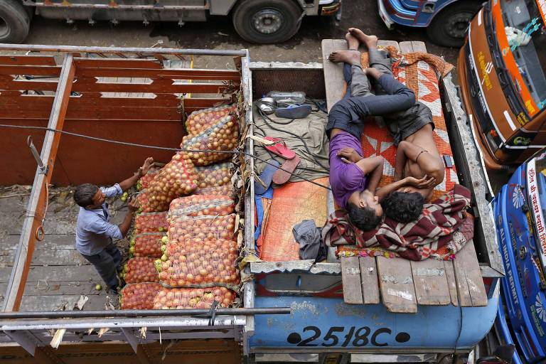 Trabalhadores dormem em caminhão de produtos agrícolas em Ahmedabad, na Índia