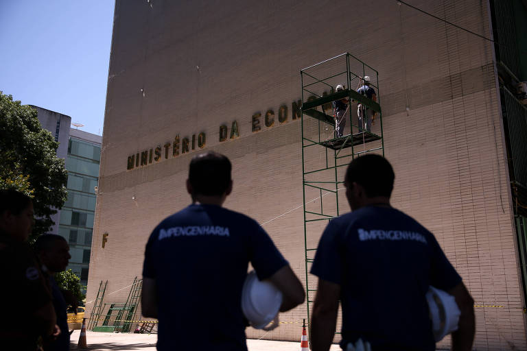 Funcionários colocam letreiro do Ministério da Economia, onde funcionava o Ministério do Trabalho