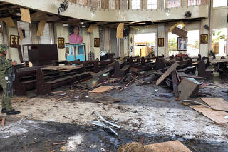 Philippine Army member inspects damage inside church after bombing attack in Jolo
