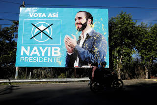 People ride past a campaign poster of GANA presidential candidate Bukele in Cojutepeque