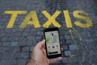 FILE PHOTO: A photo illustration shows the Uber app and a black cab in London