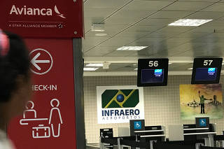 A passenger walks past the check-in desk of Avianca airlines at Afonso Pena International Airport in Sao Jose dos Pinhais