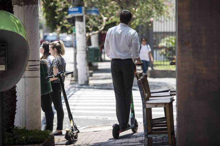 Homem anda de patinete na calcada da rua Pedroso Alvarenga