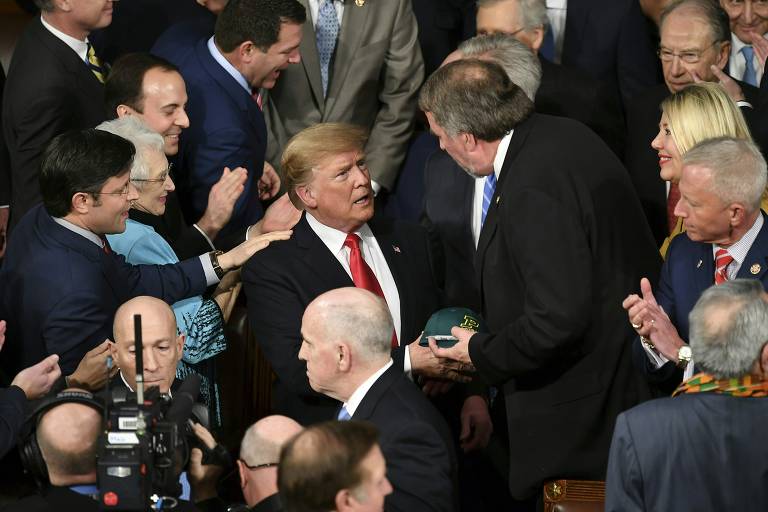 O presidente dos EUA, Donald Trump, é cumprimentado ao entrar no plenário do Congresso
