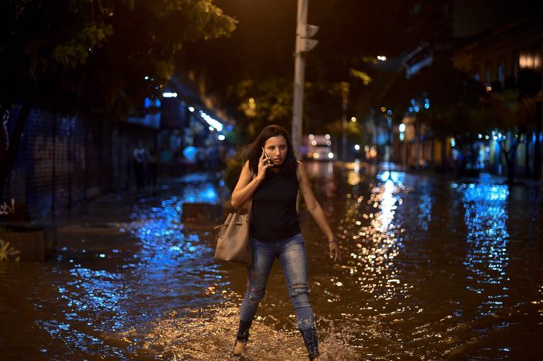 Pessoas andam em rua inundada no bairro de Botafogo, na zona sul do Rio de Janeiro, depois que uma forte chuva inundou várias áreas da cidade.