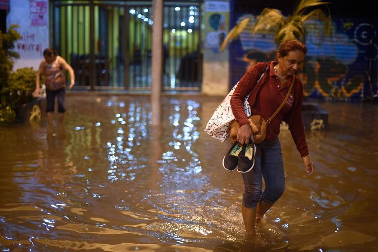 Pessoas andam em rua inundada no bairro de Botafogo, na zona sul do Rio de Janeiro, depois que uma forte chuva inundou várias áreas da cidade.