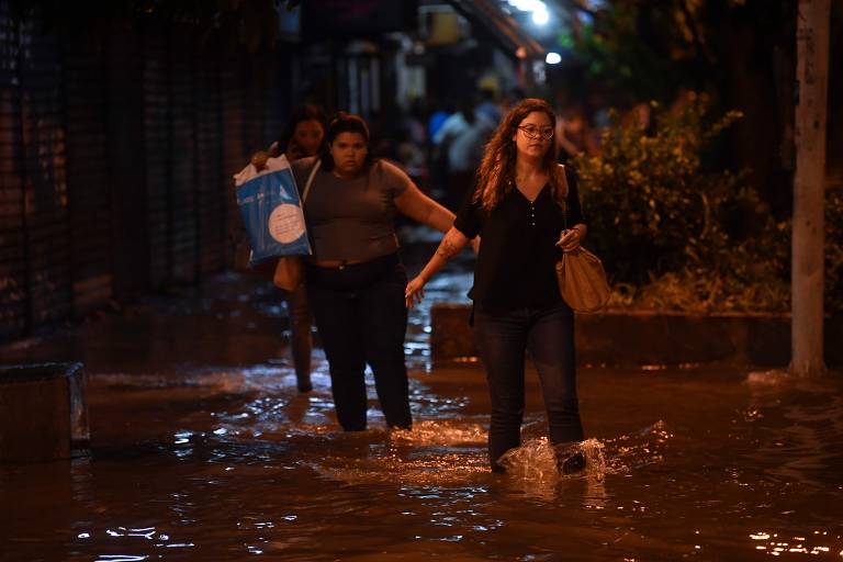 Pessoas andam em rua inundada no bairro de Botafogo, na zona sul do Rio de Janeiro, depois que uma forte chuva inundou várias áreas da cidade.