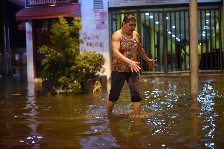 Pessoas andam em rua inundada no bairro de Botafogo, na zona sul do Rio de Janeiro, depois que uma forte chuva inundou várias áreas da cidade.
