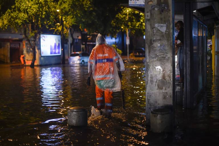 Pessoas andam na rua Voluntários da Pátria no bairro de Botafogo, na zona sul do Rio de Janeiro, depois que uma forte chuva inundou várias áreas da cidade.