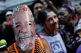 A member of the Workers' Party (PT) wears a mask depicting Brazil's former President Luiz Inacio Lula da Silva after he was given a second prison term after being convicted on a new corruption charge, in Sao Paulo