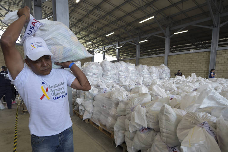 Voluntário carrega nas costas um grande pacote com mantimentos enviado pelos EUA para Cucata, Colômbia
