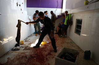 A police forensic expert checks a cloth on a blood-stained floor at a house where police officers confronted suspects during an operation against drug gangs at Fallet slum in Rio de Janeiro