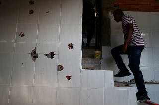 A man is seen next to the wall with bullet holes at a house where police officers confronted suspects during an operation against drug gangs at Fallet slum in Rio de Janeiro