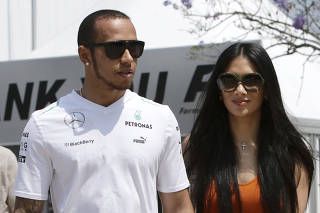 Mercedes Formula One driver Hamilton walks with girlfriend Scherzinger in the paddock before the start of the third practice session of the Malaysian F1 Grand Prix at Sepang International Circuit outside Kuala Lumpur