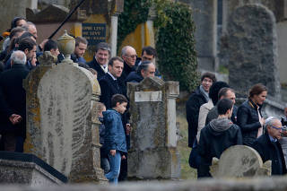 French President Emmanuel Macron walks between graves that were desecrated with swastikas and anti-Semitic slogans in the Jewish cemetery in Quatzenheim