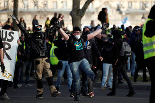 Protesters wearing yellow vests clash with French riot police near the Invalides during a demonstration by the 