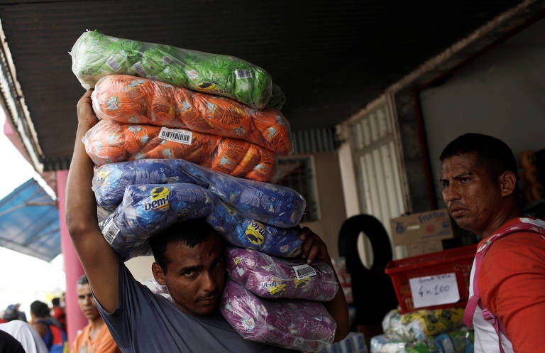 Venezuelano carrega produtos comprados no Brasil, em Paracaima, na quinta (21)