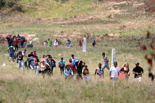 People walk through a field as they try to cross the border between Venezuela and Brazil in Pacaraima