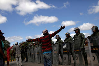 People talk with Venezuelan soldiers at the border between Venezuela and Brazil in Pacaraima
