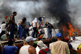 Opposition supporters unload humanitarian aid from a truck that was set on fire in Cucuta