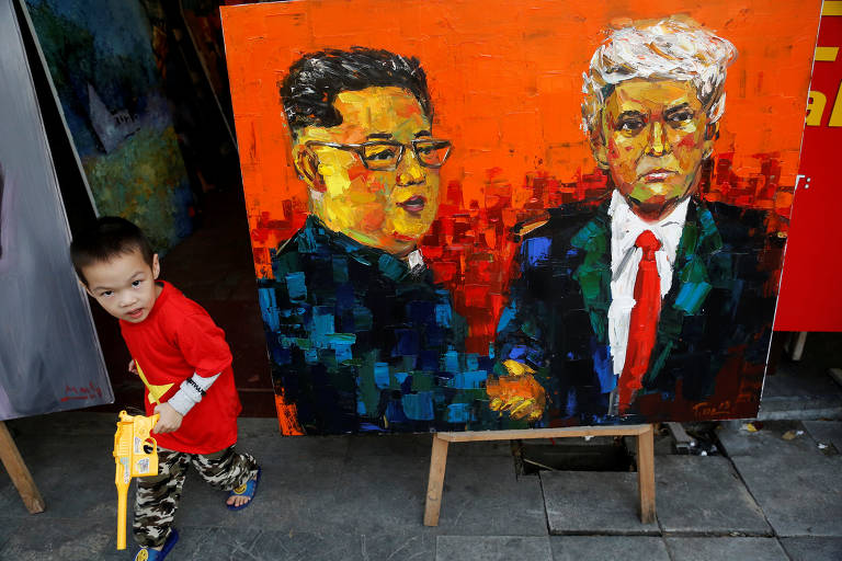 Uma criança caminha perto de uma pintura do presidente dos EUA, Donald Trump, e do ditador da Coréia do Norte, Kim Jong Un