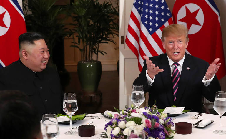 Donald Trump, gesticula enquanto ele e o ditador norte-coreano Kim Jong Un sentam-se para um jantar durante a segunda cúpula dos EUA e da Coréia do Norte em Hanói