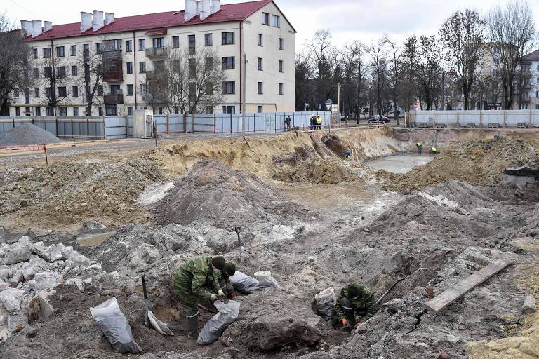 Homens trabalham na vala comum encontrada em um antigo gueto judeu, na Belarus