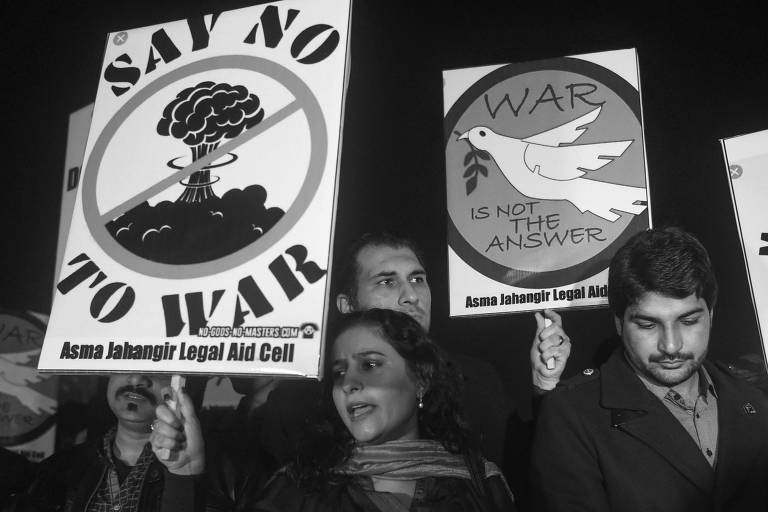 Populares seguram cartazes onde se lê "diga não à guerra" e "guerra não é a resposta" durante vigília em Lahore, no Paquistão, após acirramento de tensões entre o país e a Índia