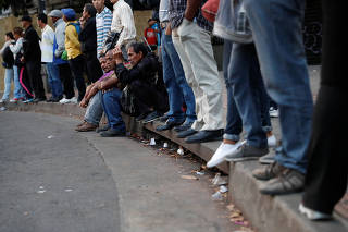 People wait for transportation during a blackout in Caracas