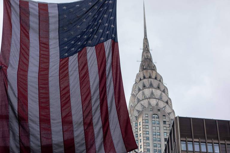 Prédio da Chrysler em Manhattan, em Nova York, com a bandeira dos EUA à frente 