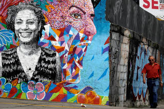Man walks past by a wall with an image of activist and councilwoman Marielle Franco in Rio de Janeiro