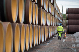 FILE PHOTO: A man walks by a stack of North Stream 2 pipes in Kotka