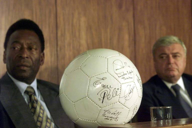 Pelé e Ricardo Teixeira à mesa separados por uma bola de futebol