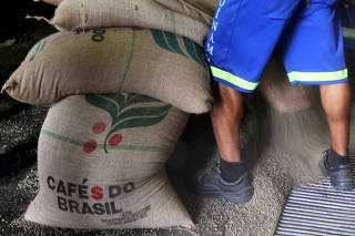 FILE PHOTO: Workers unload 60-kg jute bags of coffee beans for export in a coffee warehouse in Santos