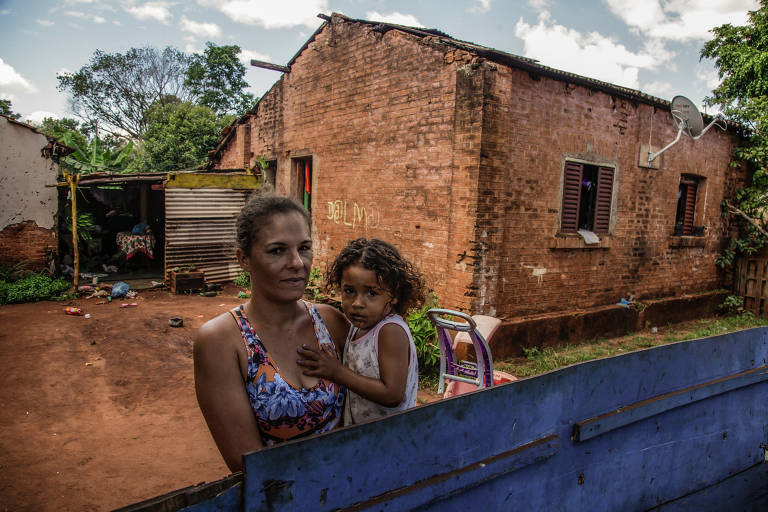 Daiane de Souza Silva segura sua filha em frente a casa que mora há 19 anos, na antiga Estação Ferroviária Capeva, em Serrana
