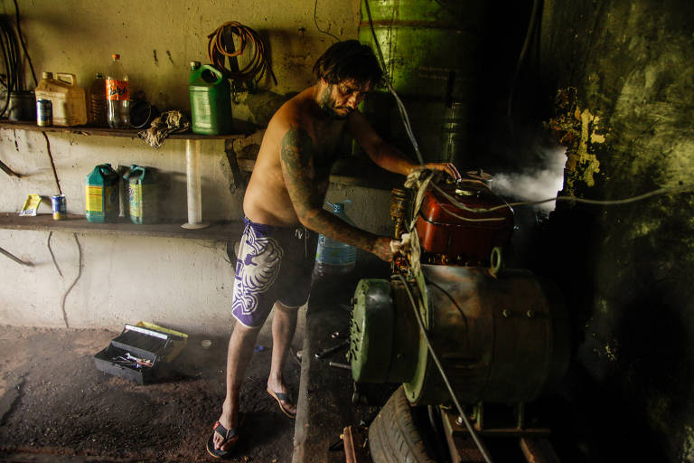 Fabrício Cesar Furtado, 38, liga um gerador a diesel na casa que ocupa na antiga estação ferroviária Águas Virtuosas