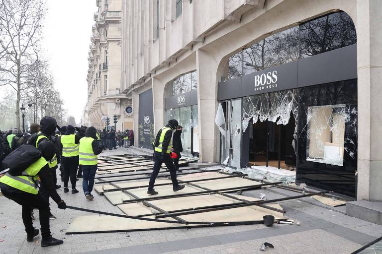 Pessoas com coletes amarelos atacam loja da Hugo Boss na avenida Champs Elysées, em Paris
