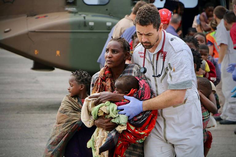 Mulher e crianças atingidas pelo ciclone recebem ajuda de voluntários, em Beira, Moçambique