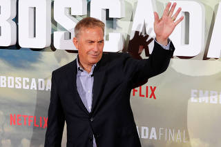 Actor Costner waves during a photocall to promote his latest film 