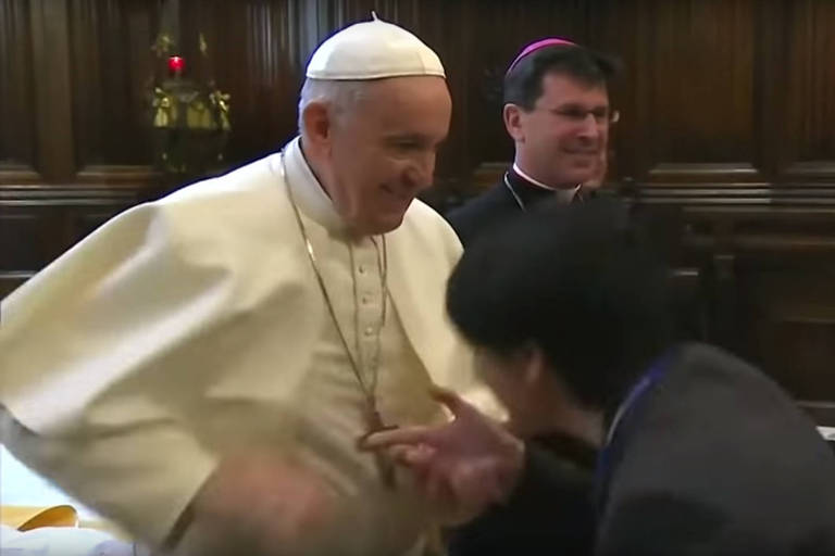 Imagem retirada de um vídeo mostra o papa Francisco recolhendo sua mão enquanto uma fiel tenta alcançá-la para beijar o anel papal