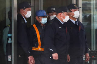 FILE PHOTO : A person believed to be former Nissan Motor Chairman Carlos Ghosn (wearing blue cap) leaves the Tokyo Detention House in Tokyo