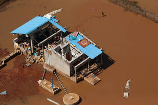 FILE PHOTO: A woman walks past a small concrete slaughterhouse as waters begin to recede in the aftermath of Cyclone Idai, in Buzi near Beira