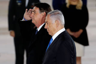 Brazilian President Jair Bolsonaro gestures as he stands next to Israeli Prime Minister Benjamin Netanyahu during a welcoming ceremony upon his arrival in Israel, at Ben Gurion International airport in Lod, near Tel Aviv, Israel
