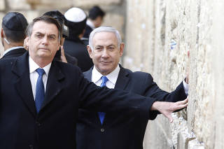 Brazilian President Jair Bolsonaro, accompanied by Israeli Prime Minister Benjamin Netanyahu, pose for a photo as they visit the Western Wall in Jerusalem's Old City