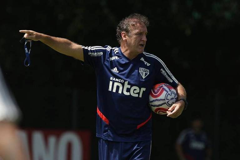 Técnico Cuca segura a bola enquanto dá orientações aos jogadores do São Paulo no CT da Barra Funda