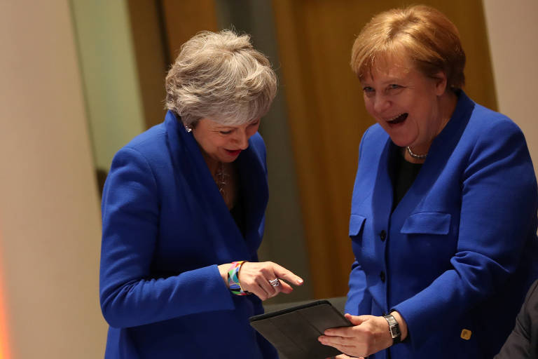 Theresa May e Angela Merkel no momento em que a chanceler alemã mostra o meme para a britânica 
