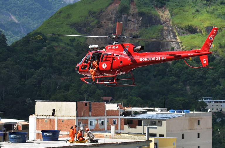 Helicóptero do Corpo de Bombeiros leva pessoa resgatada dos escombros dos dois prédios que desabaram na comunidade do Muzema, no Rio