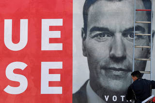 A worker places an electoral poster of Spain's Socialist leader and current Prime Minister Pedro Sanchez in La Fresneda