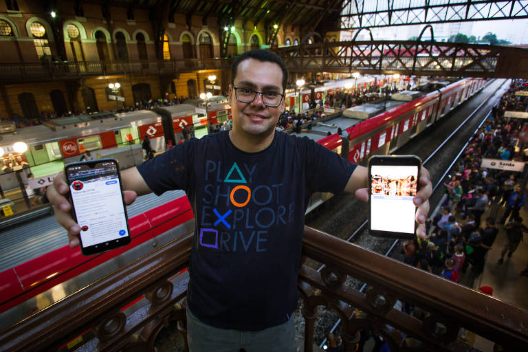 Homem mostra dois celulares com perfis de redes sociais nas telas, na estação da Luz, em São Paulo